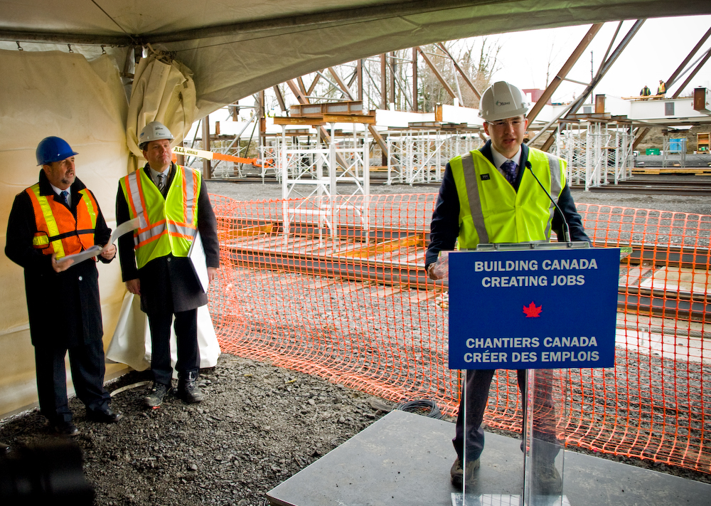 pierre-at-strandherd-bridge-site MP Pierre Poilievre, Parliamentary Secretary to the Minister of Transport, Infrastructure and Communities speaks at the construction site of the future Strandherd-Armstrong Bridge. Minister Denis Lebel and City Councillor Steven Desroches stands to the left.