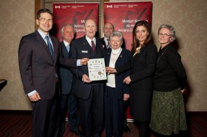 Pierre Poilievre, Member of Parliament for Nepean-Carleton and Ms. Eve Adams, Parliamentary Secretary to the Minister of Veterans Affairs present a Parliamentary Certificate to Mr. John Barclay, whose family stands beside him.